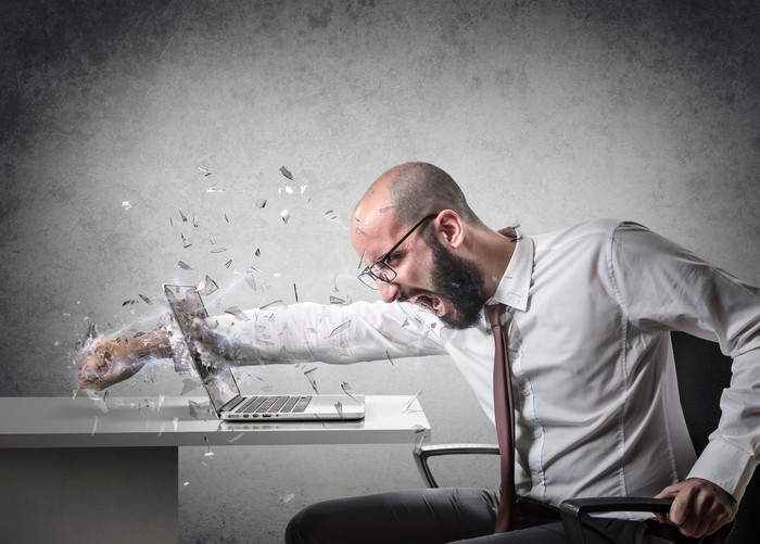 A businessman leads his fist across a laptop screen.