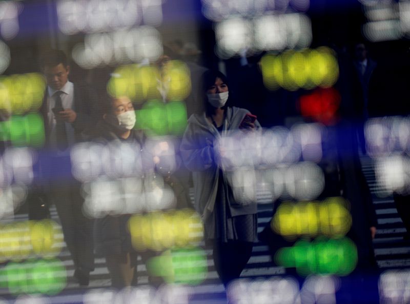 © Reuters.  File picture: Pedestrians wearing face masks are shown on an electrical panel showing stock prices outside a brokerage in a Tokyo commercial area